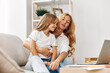 © SHOTPRIME STUDIO - Mother and daughter bonding time on the couch with a laptop, sharing laughter and learning together
