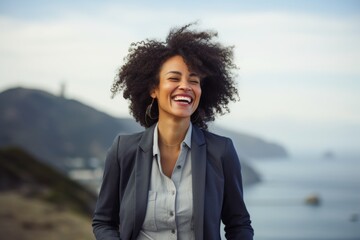 Poster - Portrait of a cheerful afro-american woman in her 30s wearing a professional suit jacket isolated in dramatic coastal cliff background