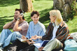 © Bliss - Three young friends, casually dressed, share a moment of laughter and conversation while sitting in a grassy park.