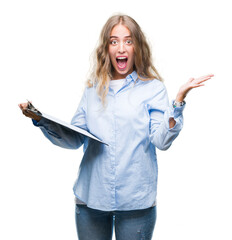 Sticker - Beautiful young blonde business woman holding clipboard over isolated background very happy and excited, winner expression celebrating victory screaming with big smile and raised hands