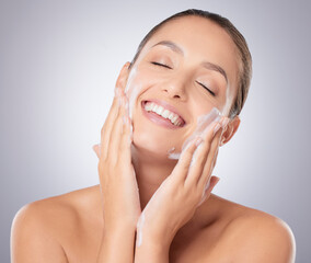 Poster - Portrait, studio and woman with smile, soap and skincare and cosmetics in beauty salon, shine and glow. Model, purple background and skin of girl, hands and treatment of dermatology and face