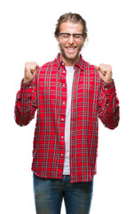 Sticker - Young handsome man with long hair wearing glasses over isolated background excited for success with arms raised celebrating victory smiling. Winner concept.