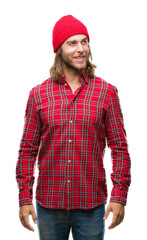 Poster - Young handsome man with long hair wearing red cap over isolated background looking away to side with smile on face, natural expression. Laughing confident.