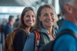 © YURY YUTY - Two women with backpacks smile while waiting in line at an airport terminal.
