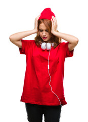 Wall Mural - Young beautiful hipster woman over isolated background wearing headphones and cap suffering from headache desperate and stressed because pain and migraine. Hands on head.