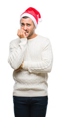 Poster - Young handsome man wearing santa claus hat over isolated background looking stressed and nervous with hands on mouth biting nails. Anxiety problem.