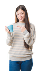 Wall Mural - Young Chinese woman over isolated background driking cup of coffee very happy pointing with hand and finger