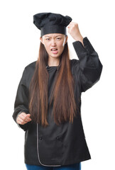 Wall Mural - Young Chinese woman over isolated background wearing chef uniform angry and mad raising fist frustrated and furious while shouting with anger. Rage and aggressive concept.