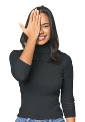 Wall Mural - Simple portrait of a young Latina having fun covering half of face with palm.