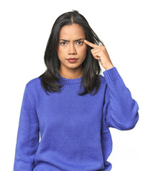 Wall Mural - simple portrait of a young latina pointing temple with finger, thinking, focused on a task.