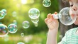 © Nattapun - Happy kid blowing bubbles, focus on, wonder and delight, ethereal, blend mode, green park backdrop