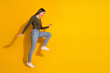 Poster - Full body photo of attractive teen woman step look empty space interested dressed stylish khaki clothes isolated on yellow color background