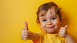 © Sourov - A cheerful toddler with bright eyes giving a thumbs up against a vibrant yellow backdrop