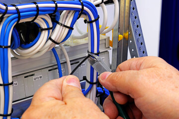 Wall Mural - Trimming a plastic screed that pulls together insulated mounting wires in electrical equipment.