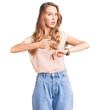 © Krakenimages.com - Young beautiful caucasian woman with blond hair wearing casual clothes in hurry pointing to watch time, impatience, upset and angry for deadline delay