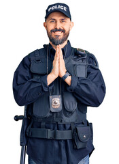 Canvas Print - Young handsome man wearing police uniform praying with hands together asking for forgiveness smiling confident.