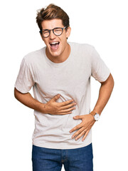 Wall Mural - Handsome caucasian man wearing casual clothes and glasses smiling and laughing hard out loud because funny crazy joke with hands on body.