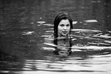 Portrait of a young beautiful dark-haired girl by the river. Black and white photo.