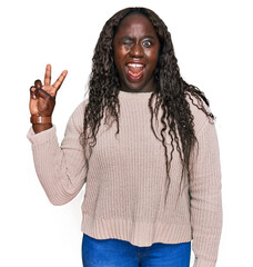 Sticker - Young african woman wearing wool winter sweater smiling with happy face winking at the camera doing victory sign with fingers. number two.