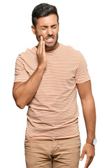 Poster - Handsome hispanic man wearing casual clothes touching mouth with hand with painful expression because of toothache or dental illness on teeth. dentist