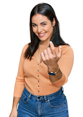 Sticker - Young hispanic woman wearing casual clothes beckoning come here gesture with hand inviting welcoming happy and smiling