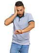 © Krakenimages.com - Handsome man with beard wearing casual clothes looking at the watch time worried, afraid of getting late