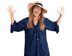 Wall Mural - Middle age hispanic woman wearing summer hat showing and pointing up with fingers number ten while smiling confident and happy.