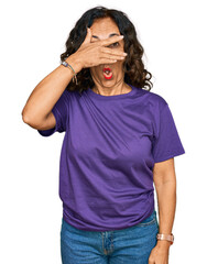 Sticker - Middle age hispanic woman wearing casual clothes peeking in shock covering face and eyes with hand, looking through fingers with embarrassed expression.