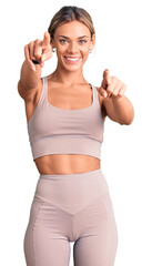 Wall Mural - Beautiful caucasian woman wearing sportswear pointing to you and the camera with fingers, smiling positive and cheerful