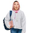 © Krakenimages.com - Hispanic woman with pink hair wearing student backpack and headphones making fish face with lips, crazy and comical gesture. funny expression.