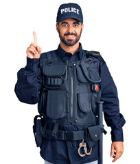 Wall Mural - Young hispanic man wearing police uniform pointing finger up with successful idea. exited and happy. number one.