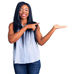 Sticker - Young african american woman wearing casual clothes amazed and smiling to the camera while presenting with hand and pointing with finger.