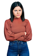 Poster - Young brunette woman with blue eyes wearing elegant sweater skeptic and nervous, disapproving expression on face with crossed arms. negative person.