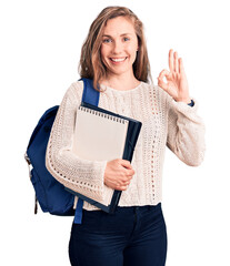 Sticker - Young beautiful blonde woman wearing student backpack holding notebook doing ok sign with fingers, smiling friendly gesturing excellent symbol