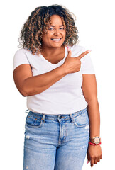 Wall Mural - Young african american plus size woman wearing casual clothes cheerful with a smile of face pointing with hand and finger up to the side with happy and natural expression on face