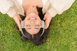 © pablo - A young woman enjoys the outdoors, lying on the grass while listening to music through her headphones.