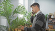© Krakenimages.com - Hispanic man with moustache in apron using phone at indoor plant shop surrounded by green foliage