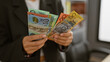 © Krakenimages.com - A professional woman holds australian currency in a modern office, depicting finance and workplace themes.