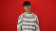 © Krakenimages.com - Handsome young hispanic man posing in a striped shirt over an isolated red background wall.
