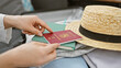 © Krakenimages.com - Close-up of a female hand placing a finnish passport into a suitcase next to a straw hat, indoors.