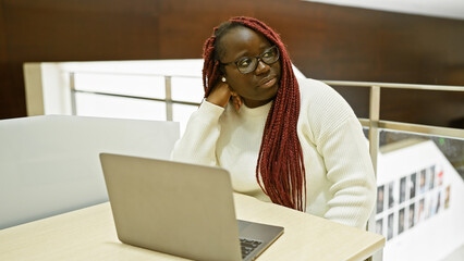 Sticker - African american woman with braids working on laptop in modern office