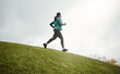 © ReeseArcurs/peopleimages.com - Music, running and woman on grass at hill for fitness, jog or healthy body in winter on mockup space. Earphones, cardio or person exercise for sport, wellness or training to workout in nature at park