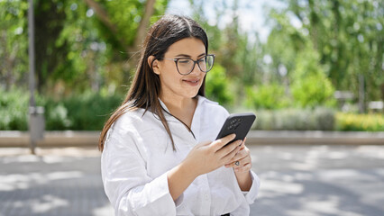 Poster - Young beautiful hispanic woman smiling happy using smartphone in the streets of Madrid