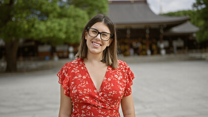 Poster - Cheerful beautiful hispanic woman with glasses posing confidently at traditional meiji temple, exuding success and joy in tokyo, japan