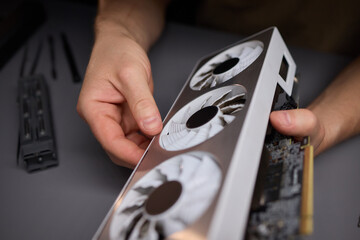 A technician is skillfully repairing a computer GPU fan with precision tools in a workshop