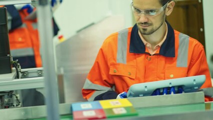 Wall Mural - Front view of professional engineer or technician worker man hold tablet and look machine working with product in robot factory.