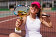 © st.kolesnikov - Excited young female tennis player celebrating victory on the card, tennis cup, victory in tennis