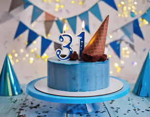 Wall Mural - A blue birthday celebration cake adorned with burning candles with number 31 age, and party ornaments	