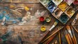 © Farid - Creative art work accessories tools supplies set on messy desk, paint brushes, paintbox watercolors crayons pencils on brown wooden artistic background, back to school. Top view, flat lay, copy space.
