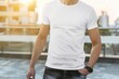 © Konstiantyn Zapylaie - A man in a white t-shirt stands on a city street, his hand in his pocket. The sunlight shines brightly, casting a warm glow on the scene